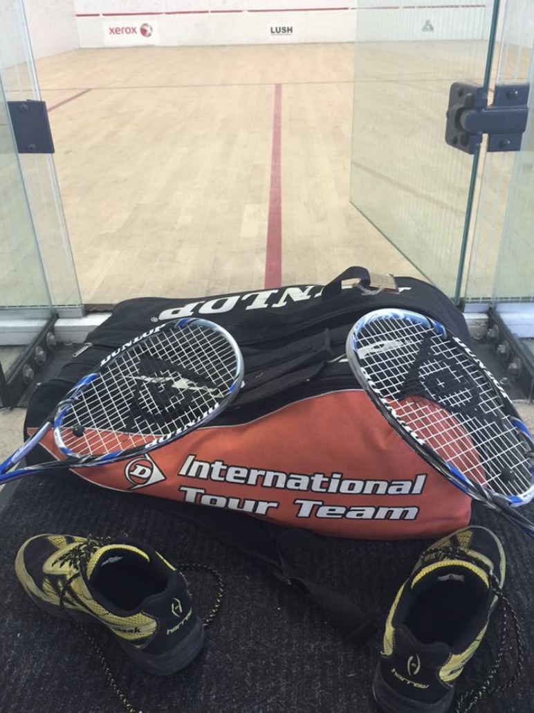 Squash racquets and shoes in front of a squash court